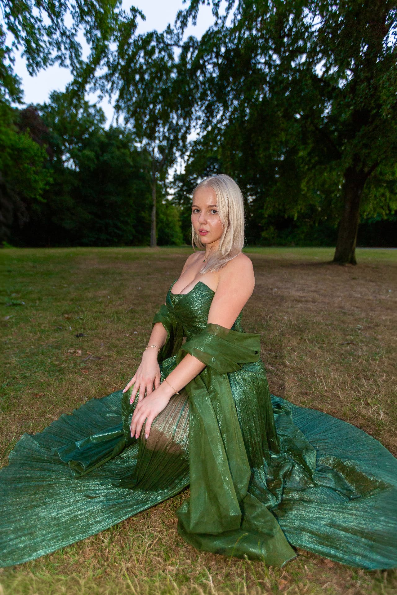 Mercedes Reuter seated in a green evening gown during an outdoor fashion campaign shoot
